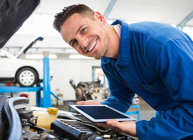 Chevrolet technicians examining coolant levels and inspecting hoses in a service center